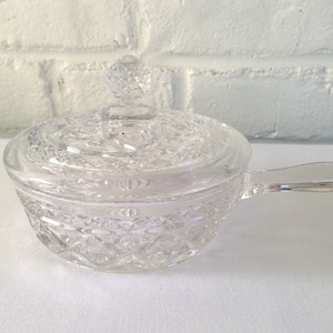 May include: A clear glass butter dish with a lid and a handle. The dish has a diamond pattern.