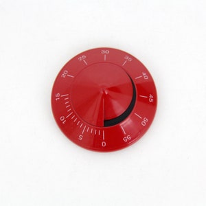 Peut inclure: Un minuteur de cuisine rouge avec un centre conique et un cadran circulaire. Des chiffres blancs indiquent les minutes de 0 à 60. La minuterie est réglée sur environ 25 minutes. Le fond est blanc uni.