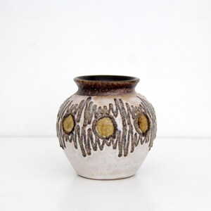 May include: A ceramic vase with a round body and a dark brown rim. The vase has a light beige base with brown textured patterns and three circular, golden-yellow accents. The interior is dark brown.