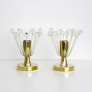 Op de afbeelding: Twee vintage tafellampen met een mid-century modern design. Elke lamp heeft een goudkleurige basis en een wit draadframe met heldere kristalachtige accenten. De lampen hebben een schakelaar op de basis.