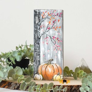 May include: A hand-painted wooden sign with a birch tree and pink leaves. Three pumpkins are at the base of the tree, one orange and two white. The sign reads "Tara Taylor Gallery".