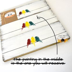 May include: A white distressed wooden sign featuring three horizontal rows, each displaying a trio of birds in red, yellow, and teal perched on a line. A brown paper band wraps around the left side. The text Linda Fehler Gallery is visible.