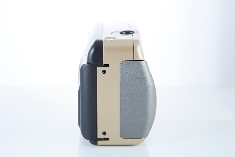 May include: A gold and black compact point-and-shoot camera with a silver lens cover.