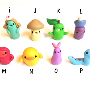 May include: A set of 10 handmade polymer clay figurines, each representing a different letter of the alphabet. The figurines are brightly colored and feature unique designs, such as a nurse, a mushroom, a pear, a duck, and a worm.