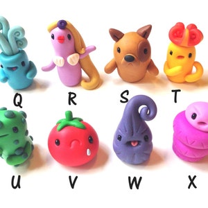 Puede incluir: Ocho figuritas de arcilla polimérica hechas a mano, cada una con un diseño y una personalidad únicos. Las figuritas están pintadas en varios colores, incluyendo azul, rosa, amarillo, verde, marrón y morado. Están dispuestas en dos filas de cuatro, con las letras Q a X debajo de cada figurita.