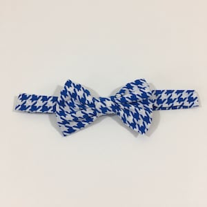 May include: A blue and white bow tie with a houndstooth pattern.