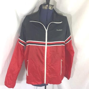 Könnte beinhalten: Eine schwarze und rote Windjacke mit einem weißen Reißverschluss und weißen Streifen. Die Jacke hat den Schriftzug "Adventure" auf der Vorderseite.