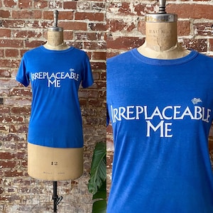 May include: A blue t-shirt with white text that reads "Irreplaceable Me".