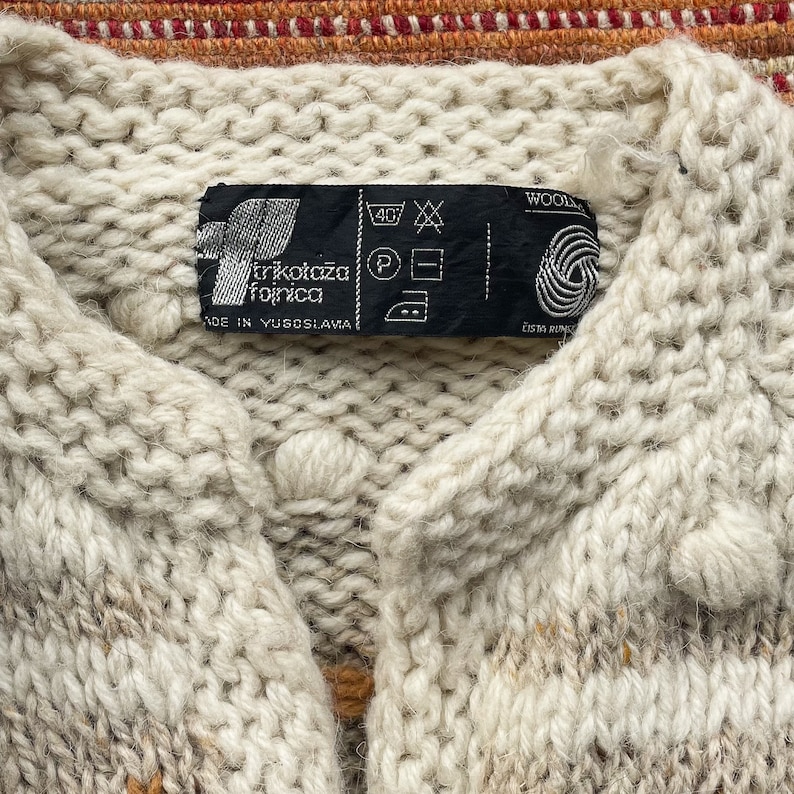 Puede incluir: Un c&aacute;rdigan de punto blanco con un patr&oacute;n blanco y marr&oacute;n. El c&aacute;rdigan tiene una etiqueta que dice "Trikot&agrave;ža  rožnica" y "Made in Yugoslavia".