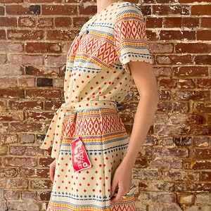 May include: A white dress with a colorful geometric pattern and a red tag that says "Ruby & You".