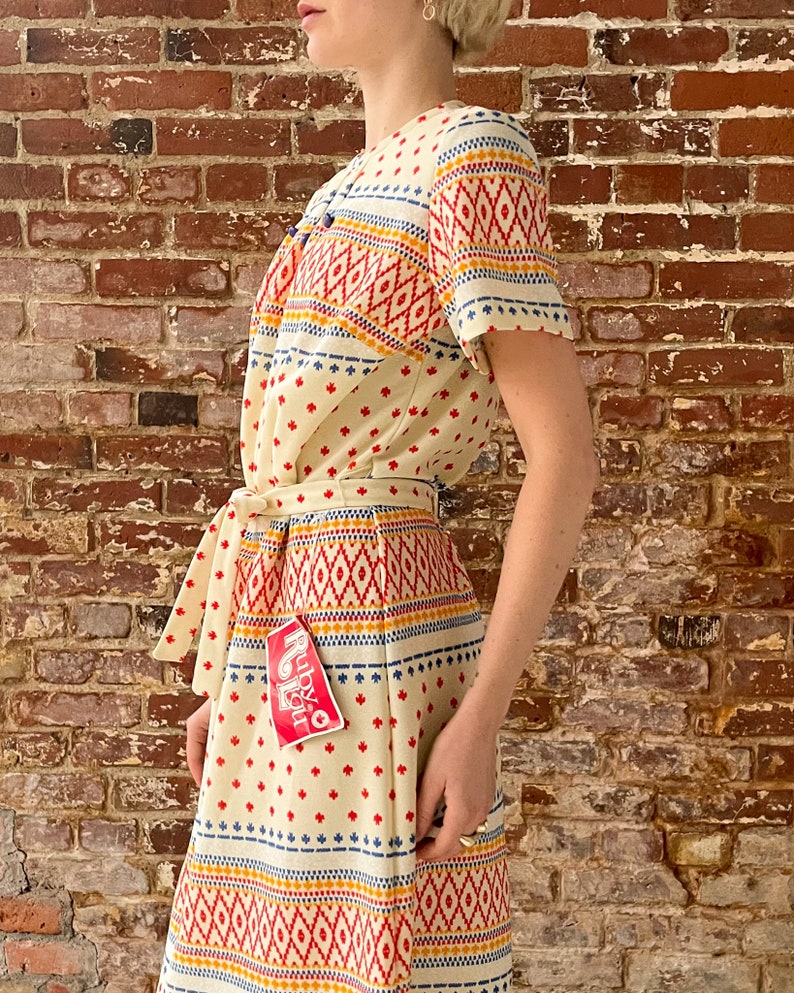 May include: A white dress with a colorful geometric pattern and a red tag that says "Ruby & You".