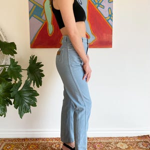 Puede incluir: Vaqueros de mezclilla azul claro con cintura alta y parche de cuero marr&oacute;n. Los vaqueros se combinan con un top corto negro y sandalias de plataforma negras. Los vaqueros tienen un dise&ntilde;o de pierna recta.