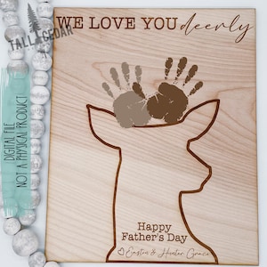 K&ouml;nnte beinhalten: Ein Holzschild mit einer Hirsch-Silhouette und zwei Handabdr&uuml;cken in Braun und Beige. Das Schild tr&auml;gt die Aufschrift "We love you dearly" und "Happy Father's Day Easton & Hunter Grace".
