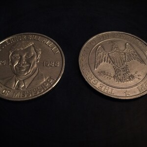 May include: Two bronze commemorative coins. One coin features a portrait of Governor Bill Allain, with the text "Governor Bill Allain 1984 1988 State of Mississippi." The other coin displays the Great Seal of the State of Mississippi, with an eagle and the text "The Great Seal of the State of Mississippi."