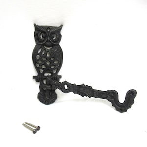 May include: Black cast iron owl-shaped cabinet pull with an ornate design. The pull features an owl perched on a branch, with an extended handle and two screws for mounting. A decorative accent for furniture.