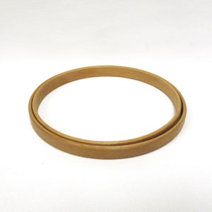 May include: A round, unfinished wooden embroidery hoop. The hoop is made of light-colored wood and has a smooth, natural finish. The inner ring fits snugly inside the outer ring, creating a secure frame for fabric.