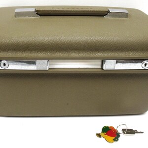 May include: Olive green vintage suitcase with a textured surface, silver-toned latches, and a handle. Includes a key with a colorful fruit charm. A classic travel accessory.