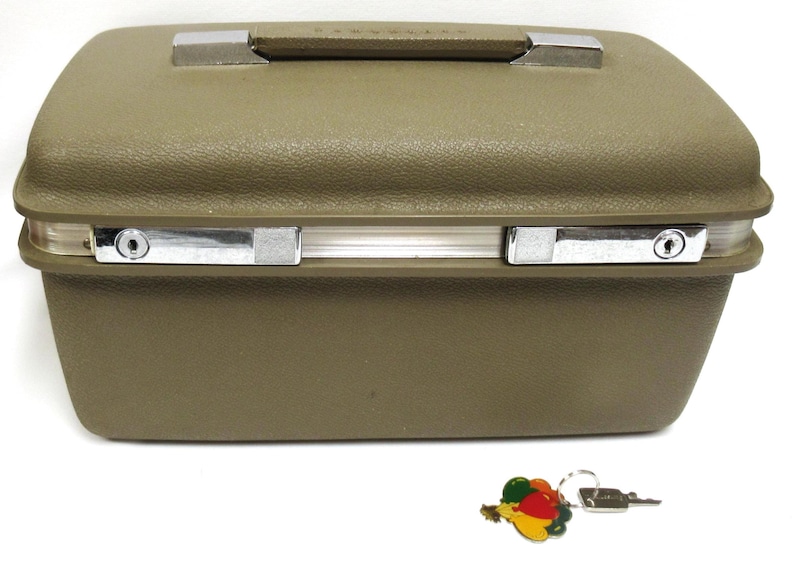 May include: Olive green vintage suitcase with a textured surface, silver-toned latches, and a handle. Includes a key with a colorful fruit charm. A classic travel accessory.