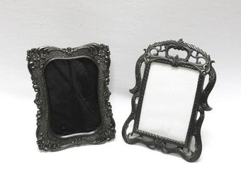 Può includere: Due cornici decorative grigio scuro. Una cornice ha un interno nero, l'altra un interno bianco. Entrambe le cornici presentano bordi dettagliati e decorativi e sono su sfondo bianco.