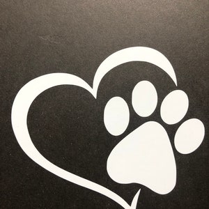 May include: White vinyl decal of a paw print inside a heart shape. The decal is on a black background.