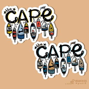 May include: Two stickers with the text "the CAPE" in black, with a variety of colourful buoys hanging below. The buoys feature nautical designs like fish, anchors, and sailboats. A small bird is perched above the word "CAPE".