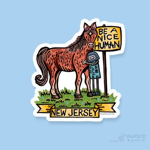 Peut inclure: Un autocollant représentant un cheval brun étreignant une petite figurine tenant une pancarte avec l'inscription "BE A NICE HUMAN". Le cheval se tient sur de l'herbe avec une bannière en dessous indiquant "NEW JERSEY". L'autocollant a une bordure blanche et un fond bleu clair.