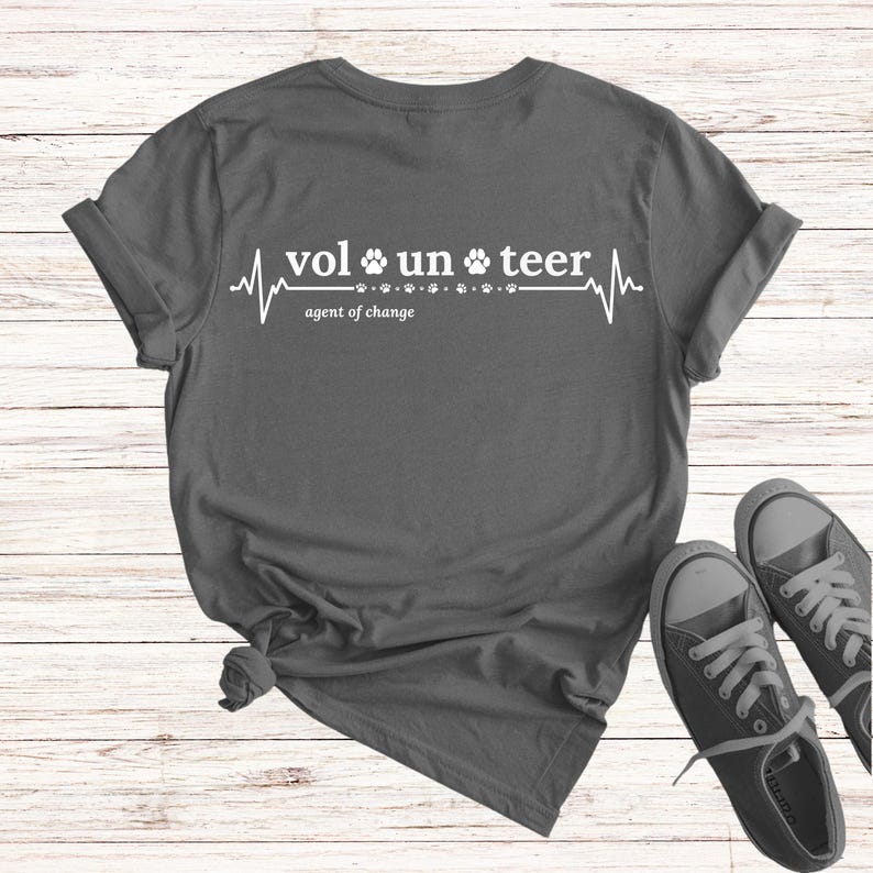 May include: Gray t-shirt with a white graphic of a heartbeat with paw prints and the text "volunteer agent of change".
