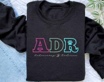 May include: Black sweatshirt with a colorful "ADR" graphic and the text "Veterinary Medicine" with a heart and paw print.