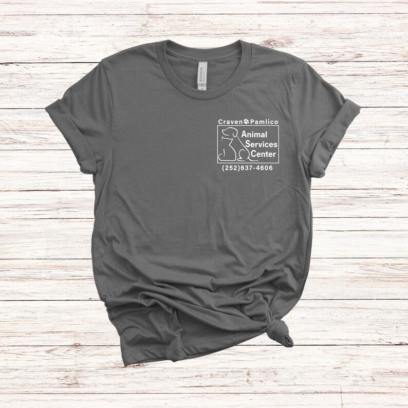 May include: A dark gray t-shirt with a white graphic of a dog and the text "Craven & Pamlico Animal Services Center (252) 637-4606"