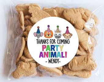 May include: A clear plastic bag filled with animal-shaped cookies featuring a round white sticker. The sticker displays four cartoon animal heads wearing party hats and the text: THANKS FOR COMING PARTY ANIMAL! - WENDY- in colorful letters.