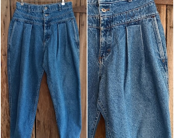 May include: Light blue denim high-waisted pants with a button fly and pleated front. The pants are hanging on a wooden hanger against a wooden background. The jeans have a classic, vintage style.