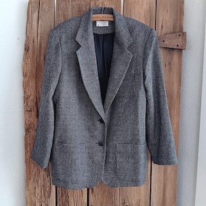 May include: A gray and white checkered blazer with a single button closure. The blazer has two pockets on the front and a black lining.