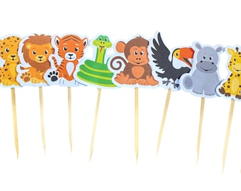 May include: A collection of colorful animal-themed cupcake toppers. The toppers feature various safari animals, including a crocodile, warthog, leopard, lion, tiger, snake, monkey, eagle, hippo, giraffe, zebra, and a black monkey. Each topper is attached to a wooden pick.