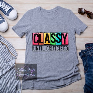 May include: A gray t-shirt with the text "CLASSY UNTIL CRITICIZED" in black letters on a colorful background.