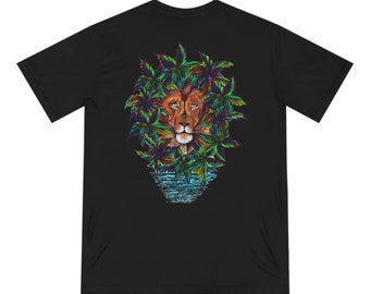 以下が含まれることがあります： 黒いTシャツ。カラフルなヤシの葉に囲まれたライオンの顔の精巧なイラスト。ライオンの顔は茶色で、葉は緑、青、黄色です。デザインには、下部に水の反射が含まれています。
