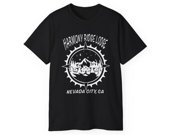 以下が含まれることがあります： 黒の半袖Tシャツ。山小屋、松の木、星空を囲むコンパスのデザインが白でプリントされています。テキストはHarmony Ridge LodgeとNevada City, CAと白のサンセリフ体で記されています。