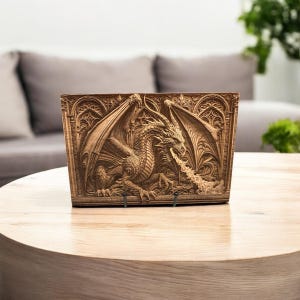 May include: A rectangular wooden carving of a dragon breathing fire. The dragon is intricately detailed with large wings and is set against an arched background. The carving is displayed on a round wooden table.