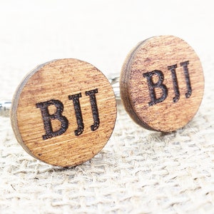 May include: A pair of wooden cufflinks with the initials "BJJ" engraved on each cufflink.