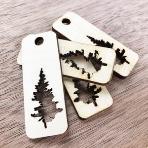 May include: Four wooden tags with a cutout design of a pine tree. The tags are light brown and have a hole at the top for hanging.