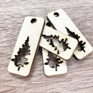 May include: Four unfinished wooden ornaments shaped like Christmas trees with a cutout design. The ornaments are stacked on top of each other.