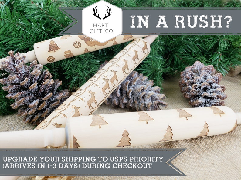 May include: Three wooden rolling pins with different engraved designs. The designs include a Christmas tree, reindeer, and a snowman. The rolling pins are on a burlap background with pine branches and pine cones.