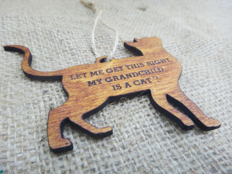 May include: Wooden cat ornament with the text "Let me get this right, my grandchild is a cat?"