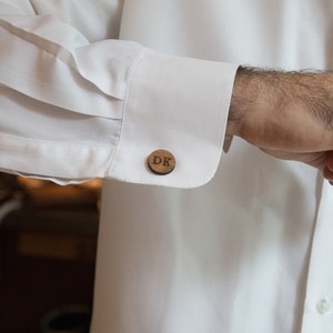 May include: A pair of wooden cufflinks with the initials "DK" engraved on them.