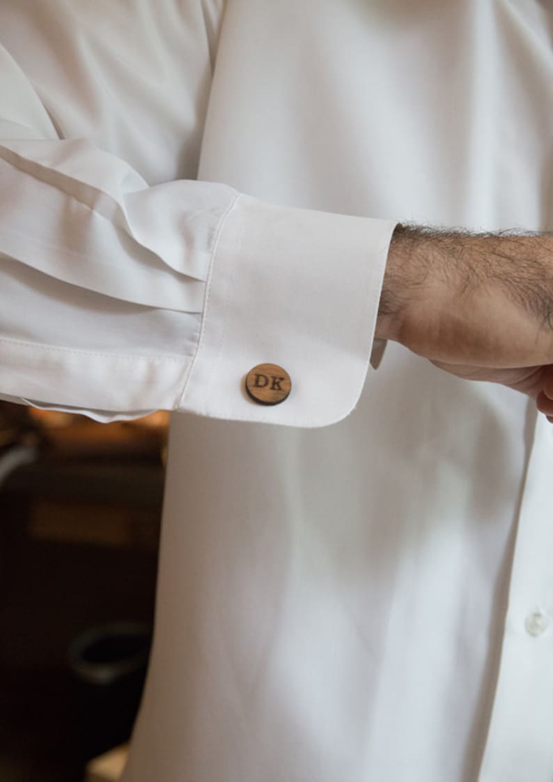 May include: A pair of wooden cufflinks with the initials "DK" engraved on them.