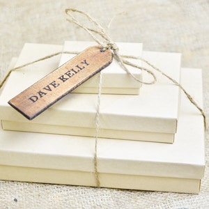May include: Three stacked boxes wrapped in twine with a wooden gift tag that reads "DAVE KELLY".