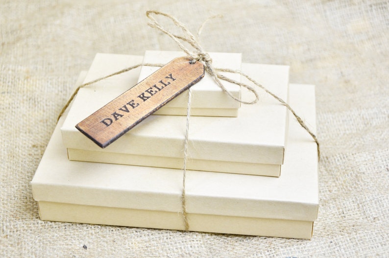 May include: Three stacked boxes wrapped in twine with a wooden gift tag that reads "DAVE KELLY".