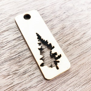 May include: A wooden tag with a cutout of a pine tree. The tag has a hole at the top for hanging.