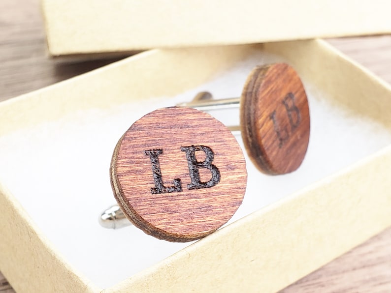 May include: A pair of wooden cufflinks with the initials "LB" engraved on each. The cufflinks are in a small box.