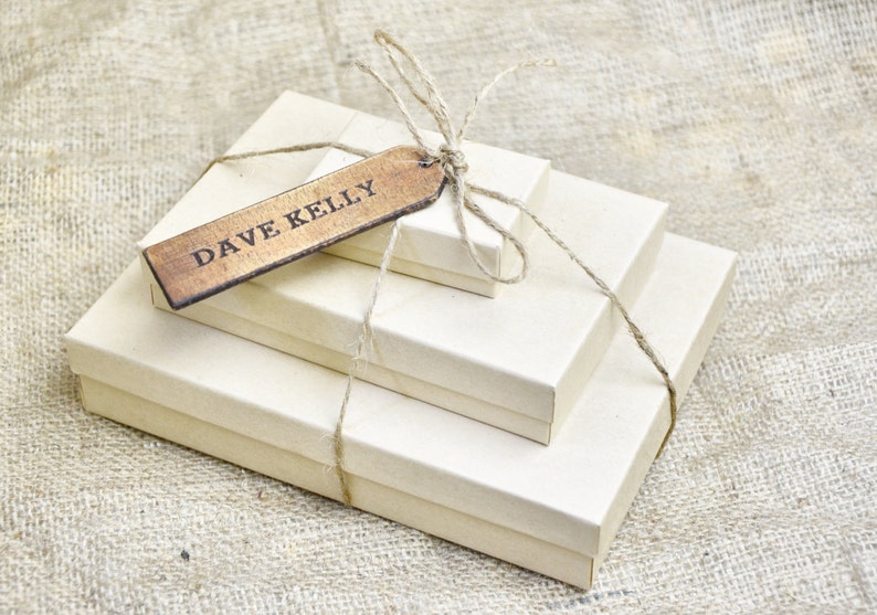 May include: Three brown cardboard boxes wrapped in twine with a wooden gift tag that reads "DAVE KELLY".