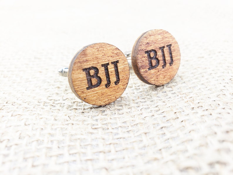 May include: A pair of wooden cufflinks with the initials "BJJ" engraved on each cufflink.